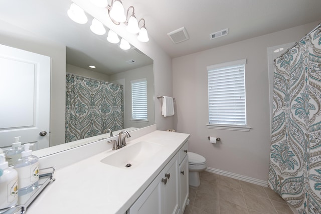 bathroom featuring a healthy amount of sunlight, toilet, tile patterned flooring, and vanity