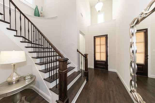 foyer featuring a towering ceiling, a healthy amount of sunlight, and dark hardwood / wood-style floors