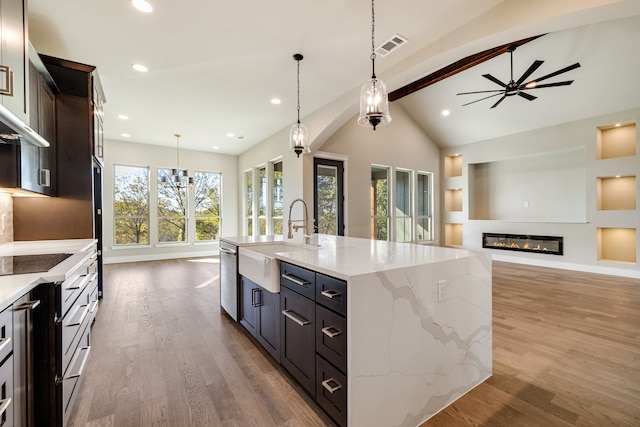 kitchen with a large island, hardwood / wood-style floors, hanging light fixtures, vaulted ceiling with beams, and sink