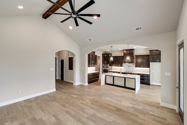 kitchen with light hardwood / wood-style flooring, hanging light fixtures, dark brown cabinets, and backsplash