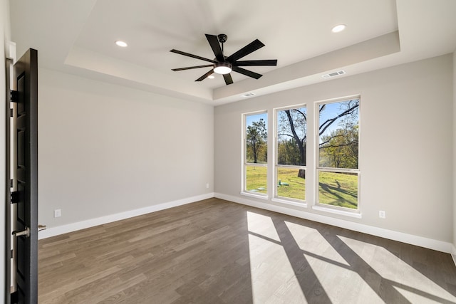 spare room featuring ceiling fan, a raised ceiling, and wood-type flooring