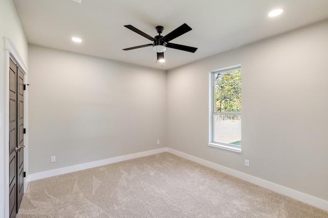 carpeted spare room with ceiling fan