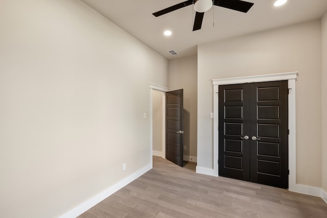 unfurnished bedroom with a closet, ceiling fan, a towering ceiling, and light hardwood / wood-style flooring