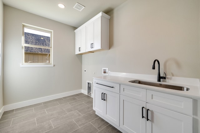 washroom featuring hookup for a gas dryer, electric dryer hookup, washer hookup, sink, and cabinets