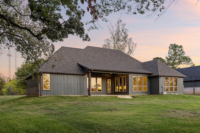 back house at dusk with a lawn