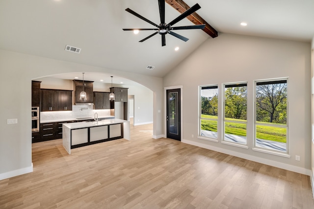 kitchen featuring sink, dark brown cabinetry, pendant lighting, light hardwood / wood-style flooring, and a kitchen island with sink