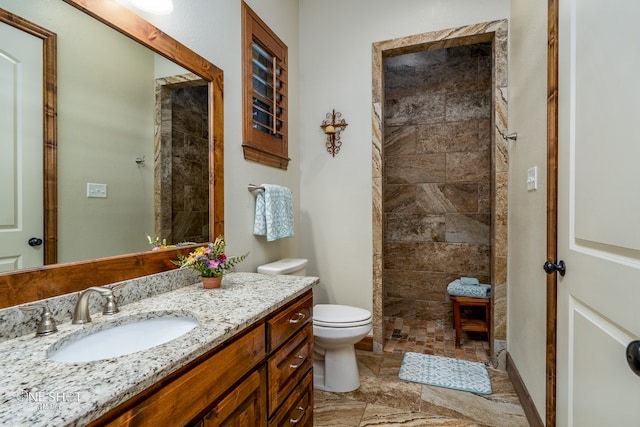 bathroom with vanity, tiled shower, tile patterned floors, and toilet