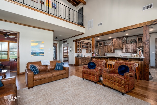 living room featuring light hardwood / wood-style floors, a towering ceiling, and ceiling fan