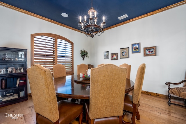 dining area featuring hardwood / wood-style flooring, a notable chandelier, and ornamental molding