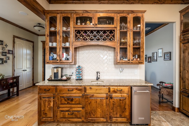 kitchen featuring sink, backsplash, light hardwood / wood-style floors, light stone countertops, and ornamental molding