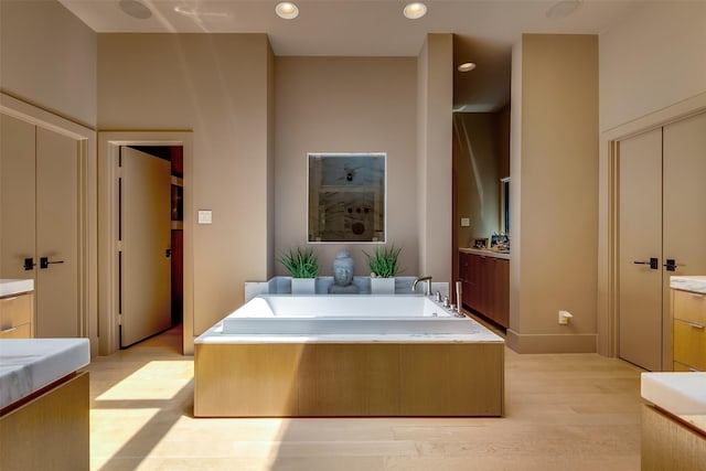 bathroom with hardwood / wood-style flooring, a tub to relax in, and vanity