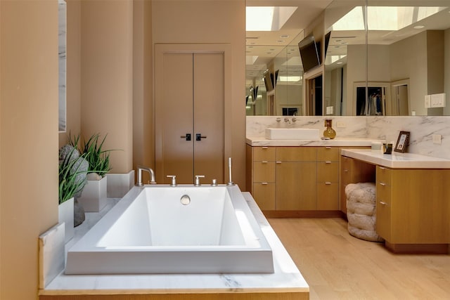 bathroom featuring vanity, a washtub, and hardwood / wood-style flooring