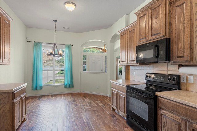 kitchen featuring black appliances, a healthy amount of sunlight, decorative backsplash, and dark wood-type flooring