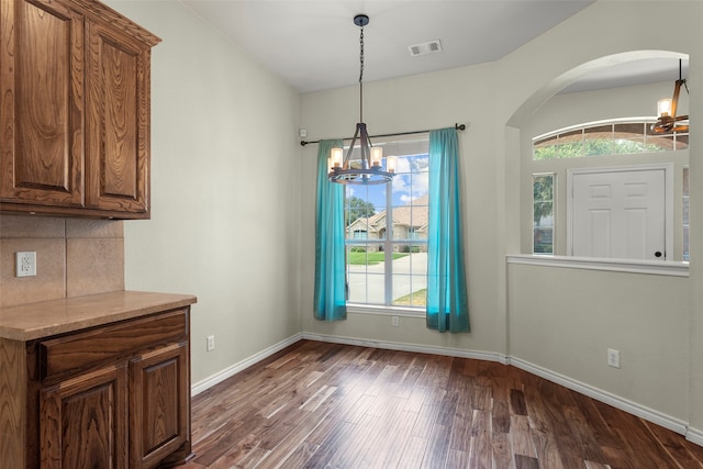 unfurnished dining area featuring an inviting chandelier and dark hardwood / wood-style floors