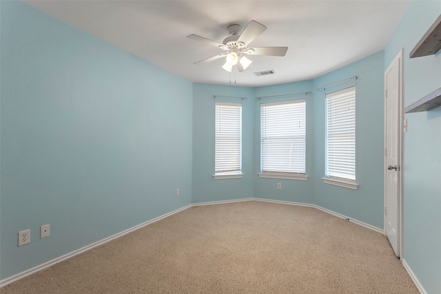 spare room with a wealth of natural light, ceiling fan, and carpet flooring