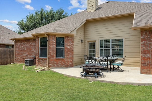 rear view of property with a lawn, a patio area, and an outdoor fire pit