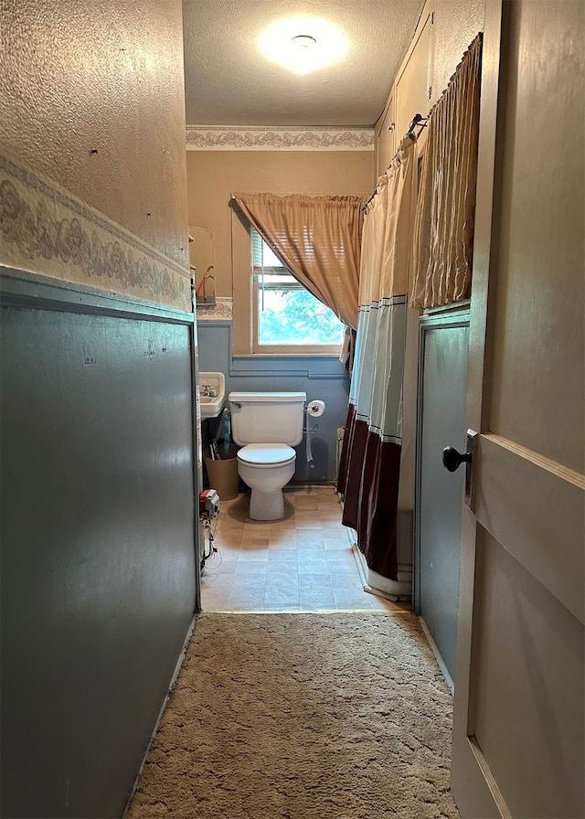 bathroom featuring toilet, a textured ceiling, and tile patterned flooring