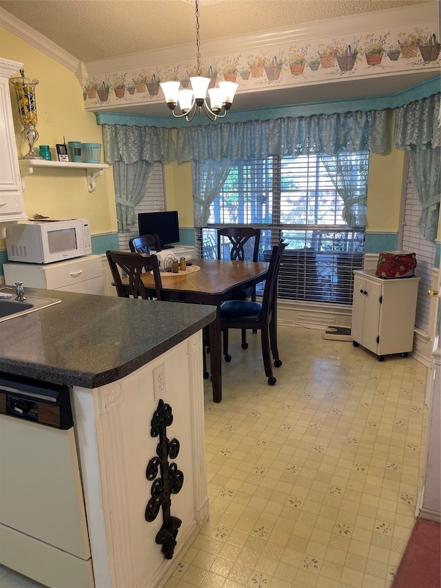 interior space with a notable chandelier, decorative light fixtures, white cabinets, white appliances, and a textured ceiling