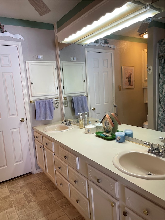 bathroom with toilet, tile patterned flooring, dual bowl vanity, and ceiling fan