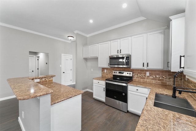 kitchen featuring appliances with stainless steel finishes, sink, white cabinetry, light stone countertops, and a center island