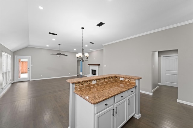 kitchen with white cabinetry, light stone countertops, a center island, dark hardwood / wood-style floors, and lofted ceiling