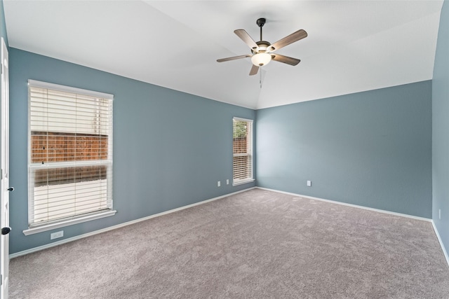 carpeted empty room with ceiling fan, plenty of natural light, and lofted ceiling