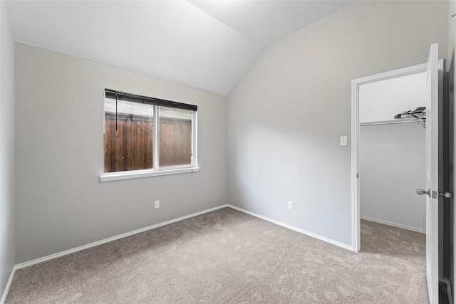 carpeted empty room featuring vaulted ceiling