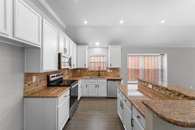 kitchen featuring dark stone countertops, stainless steel appliances, white cabinetry, and sink