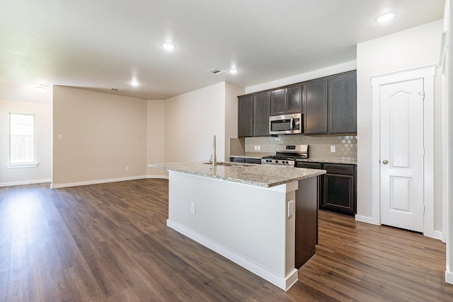 kitchen featuring a center island with sink, stainless steel appliances, dark hardwood / wood-style floors, dark brown cabinets, and sink