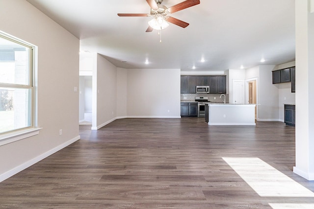 unfurnished living room with ceiling fan, sink, and dark hardwood / wood-style floors