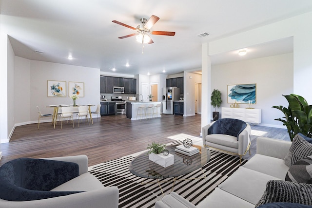 living room with dark wood-type flooring, sink, and ceiling fan