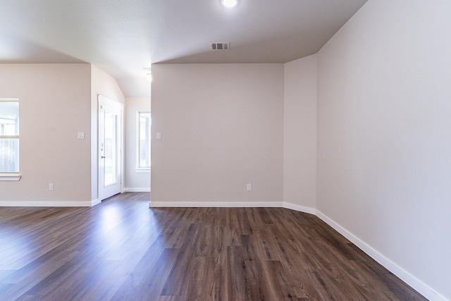 empty room featuring dark wood-type flooring, a wealth of natural light, and lofted ceiling