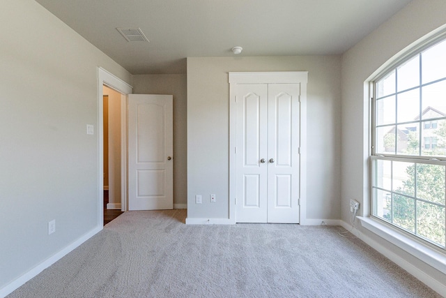 unfurnished bedroom featuring light carpet and a closet