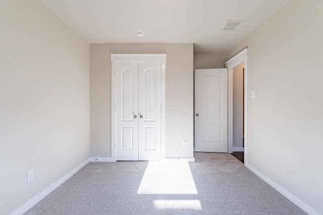 unfurnished bedroom featuring light carpet and a closet