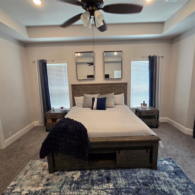 bedroom with a tray ceiling, carpet, and ceiling fan