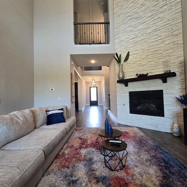 living room featuring a stone fireplace, hardwood / wood-style flooring, and a high ceiling