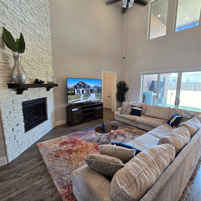 living room with ceiling fan, a fireplace, dark hardwood / wood-style flooring, and a high ceiling