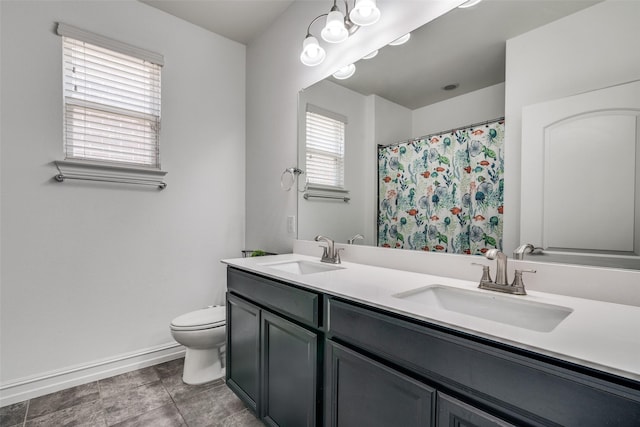 bathroom featuring a wealth of natural light, dual vanity, toilet, and tile patterned floors