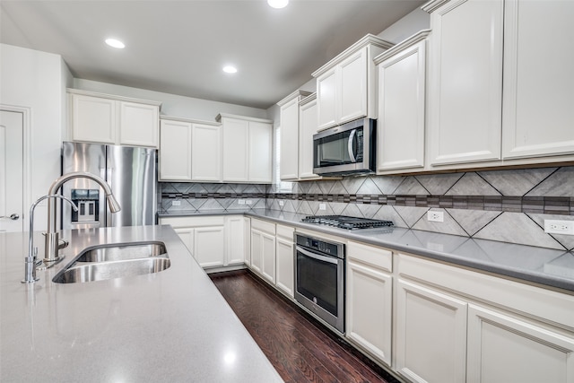 kitchen featuring white cabinetry, stainless steel appliances, dark hardwood / wood-style flooring, sink, and backsplash