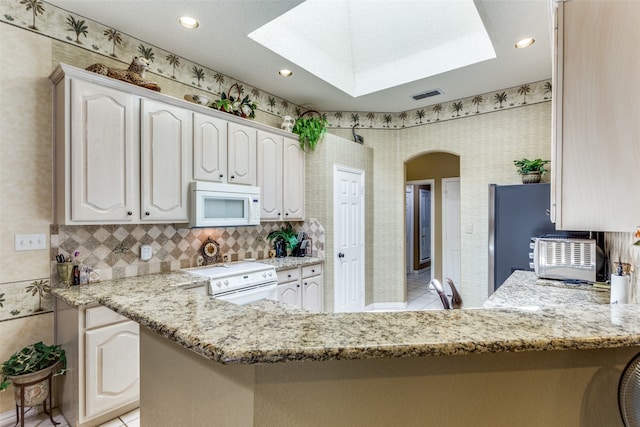 kitchen featuring kitchen peninsula, white appliances, and light tile patterned floors