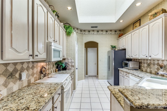 kitchen featuring light tile patterned floors, sink, decorative backsplash, and white appliances