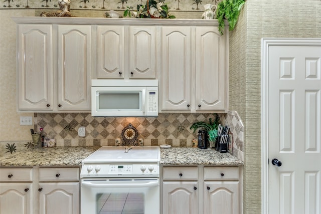 kitchen featuring tile patterned floors, tasteful backsplash, light stone countertops, and white appliances