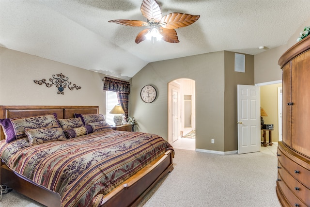 bedroom with ensuite bath, a textured ceiling, light carpet, ceiling fan, and lofted ceiling