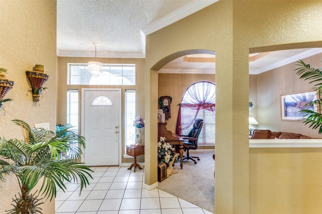 tiled entryway with a textured ceiling, a notable chandelier, and crown molding