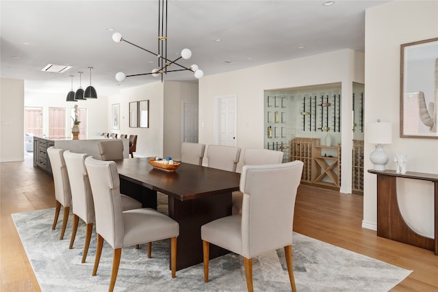 dining space with light hardwood / wood-style floors and a chandelier