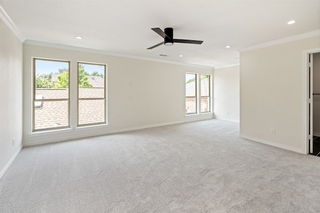 carpeted spare room featuring a wealth of natural light, crown molding, and ceiling fan