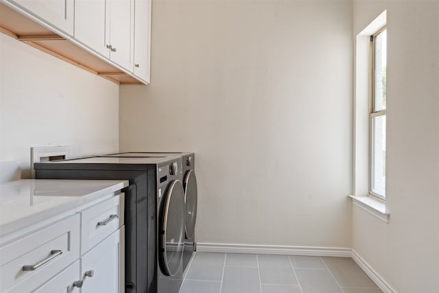 clothes washing area featuring cabinets, separate washer and dryer, and light tile patterned floors