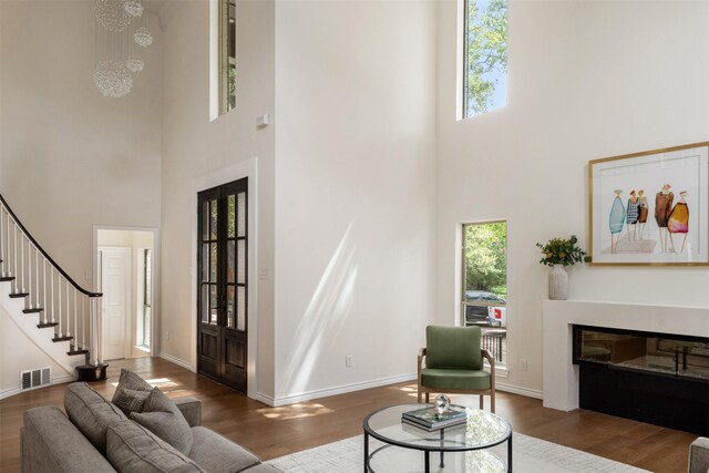 living room with a wealth of natural light, wood-type flooring, and a high ceiling