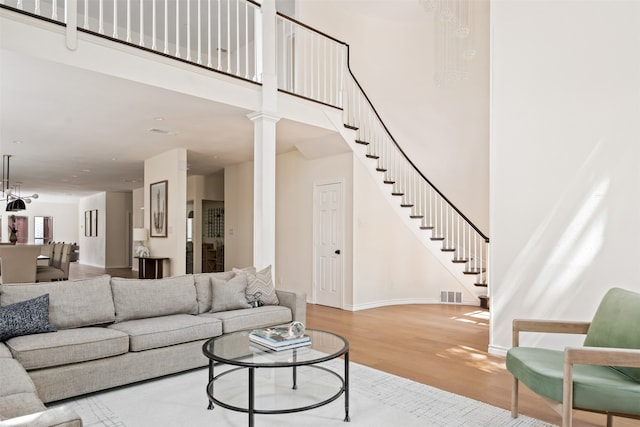 living room with decorative columns, a high ceiling, and wood-type flooring