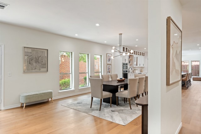 dining space featuring light hardwood / wood-style floors and an inviting chandelier